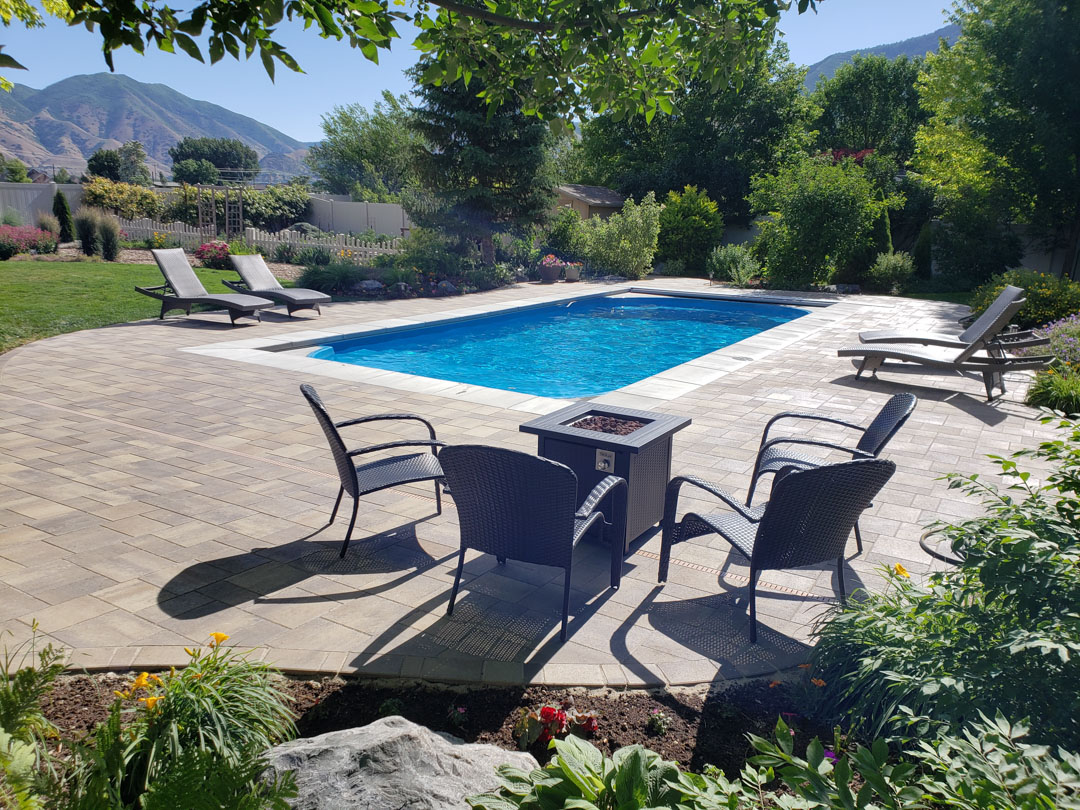 Fiberglass pool with custom hardscaping surrounding it in a Indiana backyard